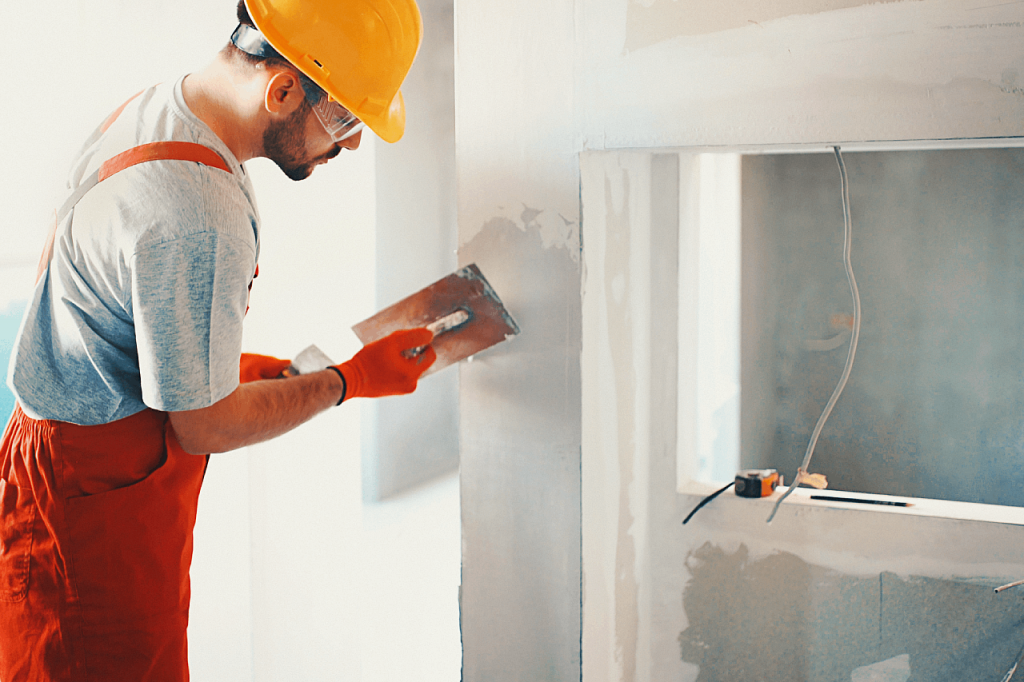 homme en train d enduire mur blanc avec casque jaune 1024x682